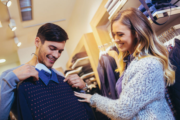 Young man consults with girlfriend while selecting a sweater Young man consults with girlfriend while selecting a sweater